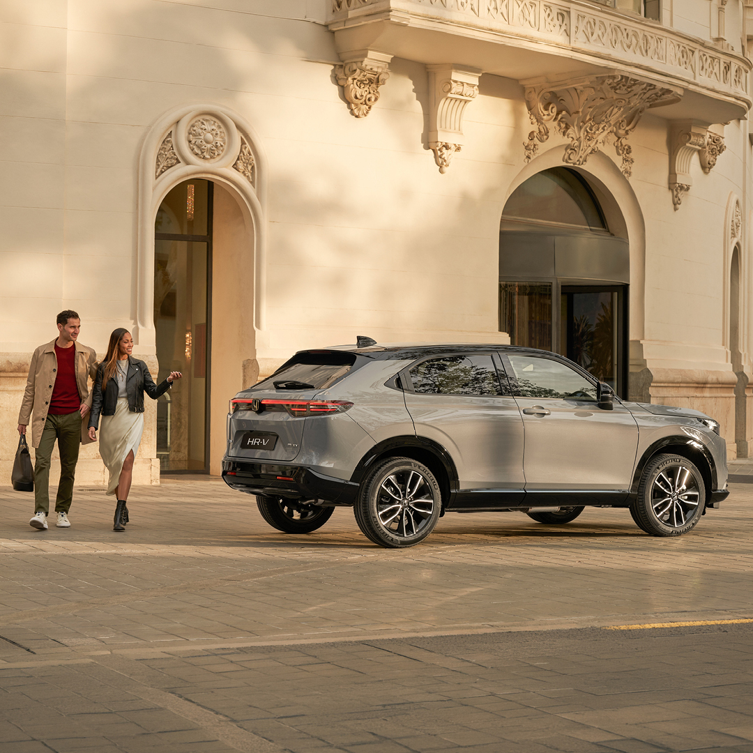 Pareja andando al lado de un HR-V estacionado en el exterior, junto a un edificio.